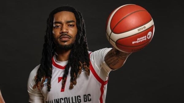 Latrell Jossell holding a basketball in one hand towards the camera.