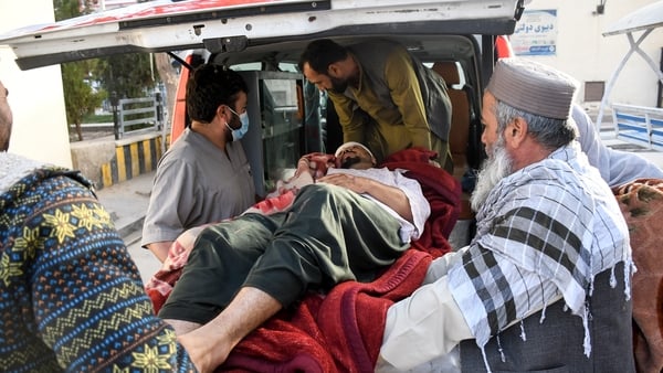 Afghan men assist an injured man into an ambulance in the aftermath of an earthquake