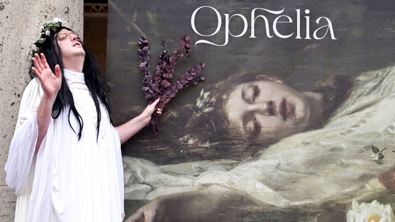 A fan of Taylor Swift poses next to a banner with the title 'Home of Taylor Swift's Ophelia'