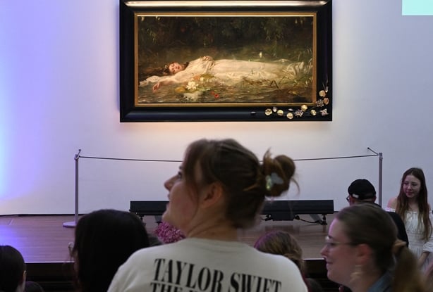 Fans of US singer-songwriter Taylor Swift and other visitors listen to a lecture about the painting 'Ophelia'