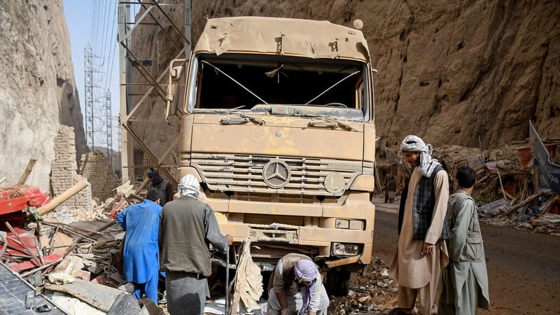 Afghan men check a damaged truck along a highway, following the earthquake