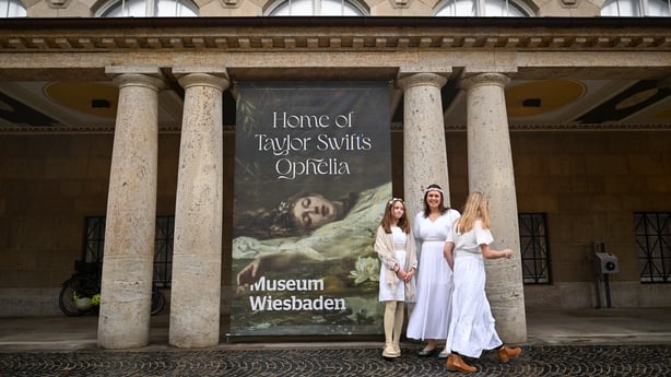 Taylor Swift fans pose next to a placard with the title Home of Taylor Swift's Ophelia outside the Museum Wiesbaden in Wiesbaden, Germany on November 2, 2025 where the painting Ophelia (circa 1900) by German artist Friedrich Heyser is displayed for a short guided tour for the so-called Swifties