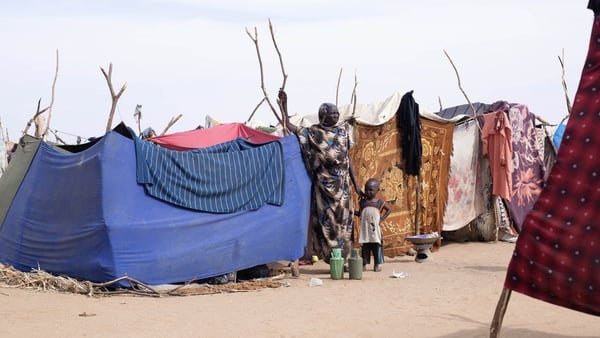 A displaced Sudanese woman and child stand near a make shift shelter after fleeing El-Fasher