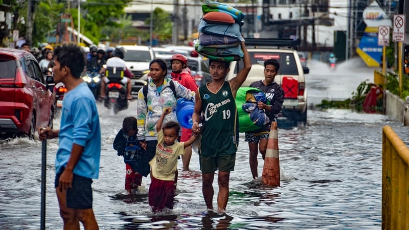 Residents carrying their belongings wade through a flooded street in Mandaue city, Cebu province