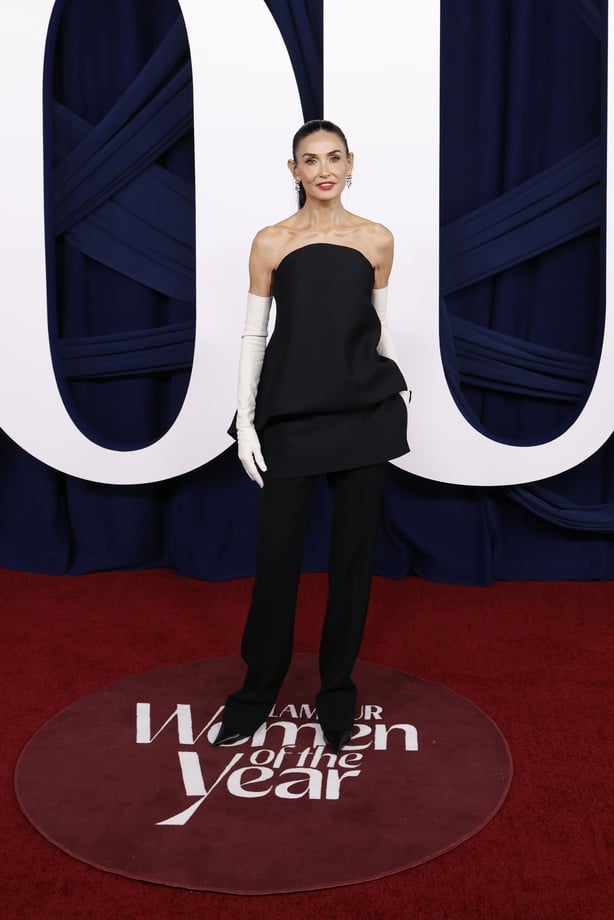 Demi Moore wears a black strapless top and black trousers with white gloves