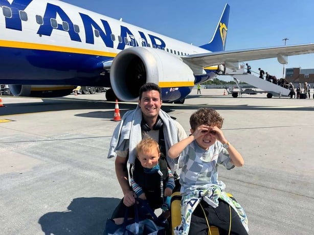 A dad and his two children posing in front of a Ryanair plane