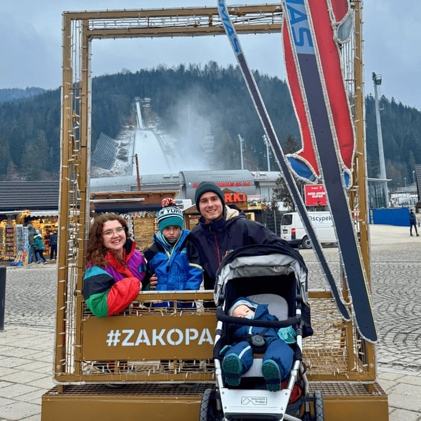 A couple and their two children posing for a photo at a ski resort in Poland