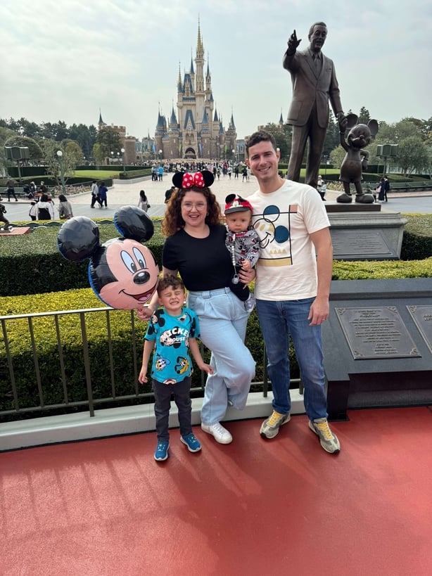 A couple and their two children posing for a photo at Disneyland