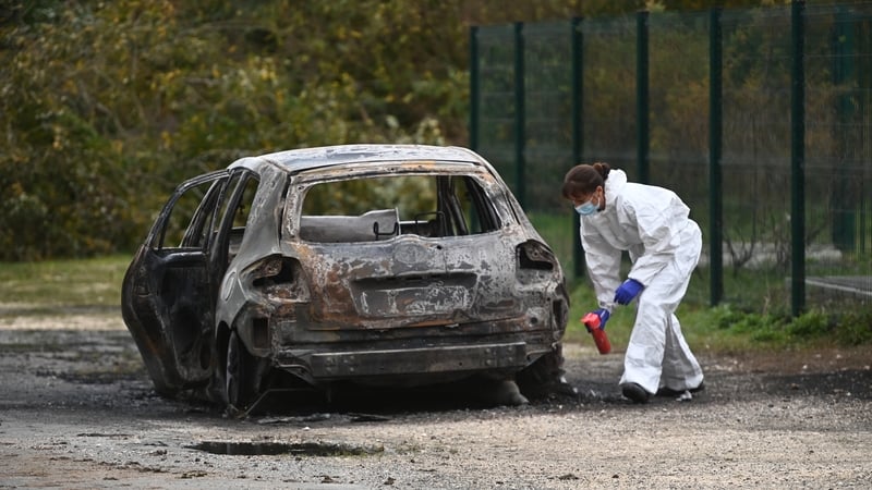 Forensic police inspect a burnt out car following the incident