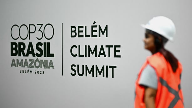 A worker walks past a banner with the COP30 UN Climate Change Conference logo in Belém
