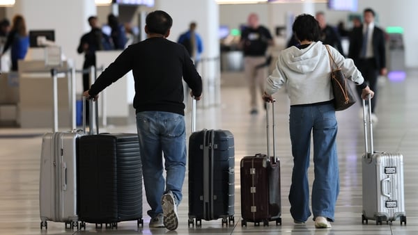 People with luggage walk through LaGuardia Airport.