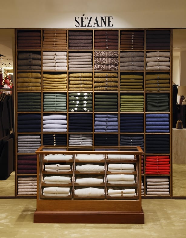 A wall of shelves holding folded cardigans and jumpers in a range of colours at the Sezane pop-up in Brown Thomas, Dublin 