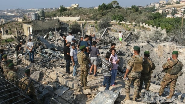 Lebanese soldiers and local residents stand at the site of an Israeli airstrike in the southern Lebanese village of Toura 