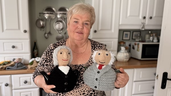 Image shows Susan Banks holdings crocheted tea cosies made in the likeness of President Michael D Higgins and president-elect Catherine Connolly