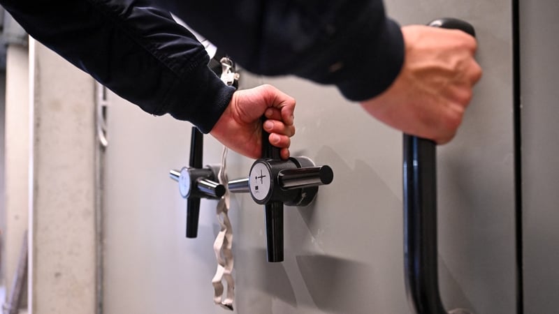 An employee opens a massive security door inside the storage room of Tradium