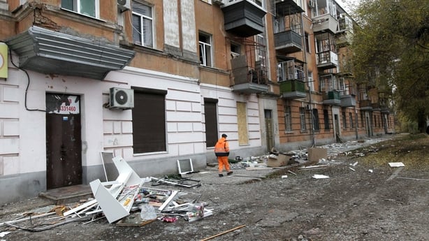 A municipal worker removes the rubble outside an apartment block damaged by a Russian drone attack in Dnipro, Ukraine