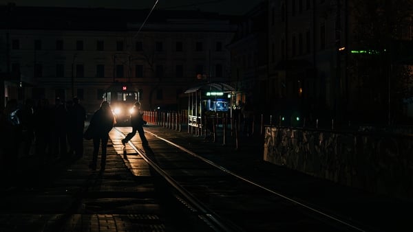 People walk through the darkened streets of Podil district amid power outages following Russian strikes on Kyiv, Ukraine