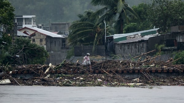 A man walks past debris along the shores of a river at Polangui in Albay province