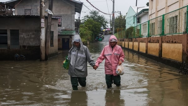 A couple wade through a flooded street as super Typhoon Fung-Wong (Uwan) hits the Philippines