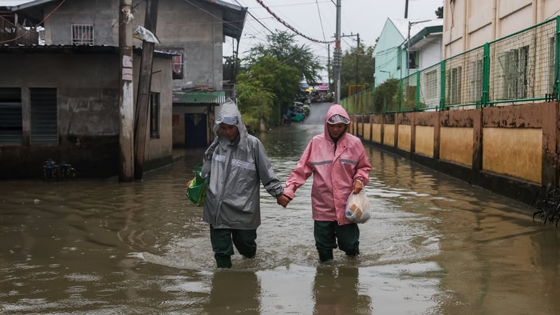 A couple wade through a flooded street at a flood-prone area in Bulacan