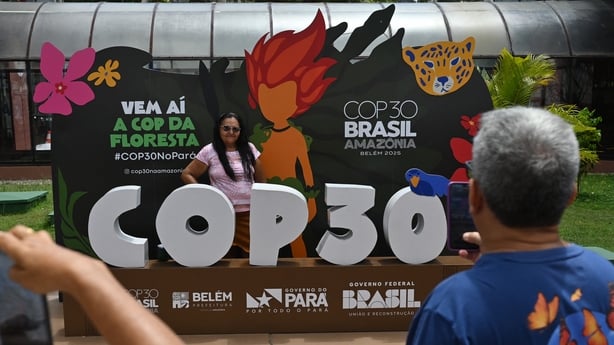 A tourist poses for a picture with COP30 mascot inside the Estacao das Doca