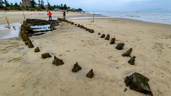 People stand next to a centuries-old shipwreck