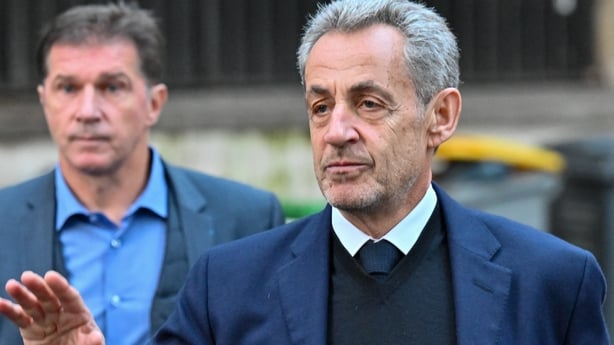 Nicolas Sarkozy gestures with an unnamed man in the background