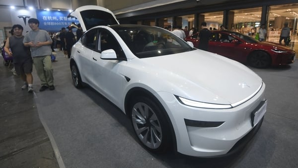 People walk past a while Tesla car at at Chinese car show