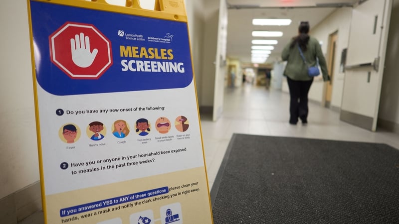 A person walks past a measles screening sign near an entrance at Victoria Hospital in London, Ontario