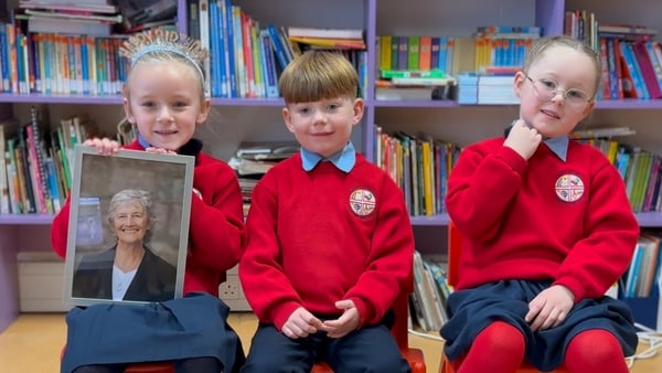 Three pupils from St Ultan’s School in Ballyfermot, Dublin sit together with a framed image of Catherine Connolly