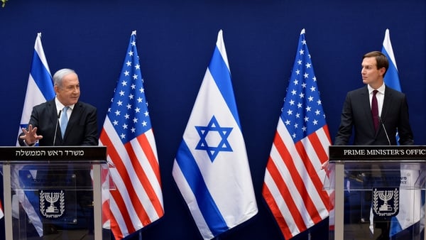Israeli Prime Minister Benjamin Netanyahu and US Presidential Adviser Jared Kushner each stand in front of a podium. Israeli and American flags are in the background.