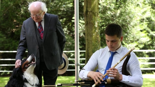 President Michael D Higgins with his dog Bród listen to piper Cormac Keegan