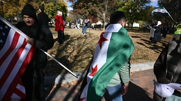 People hold American and Syrian flags across the street from the White House