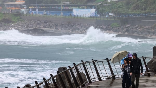 People use umbrellas to shield from the rain and the wind as Typhoon Fung-wong approaches in Taiwan