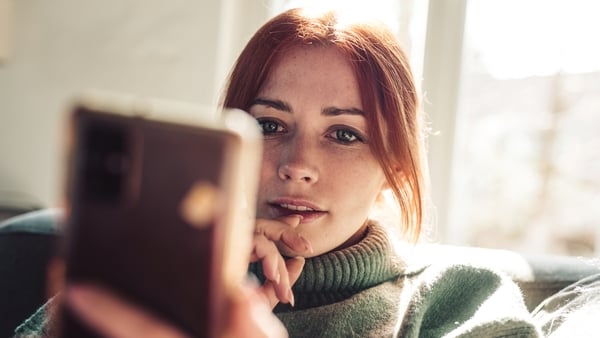 Woman with red hair looking on screen of her mobile phone.