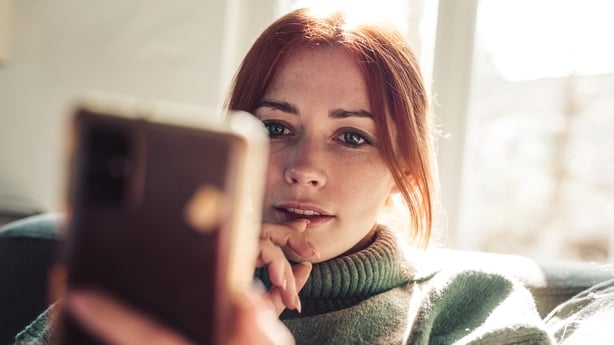 Woman with red hair looking on screen of her mobile phone.