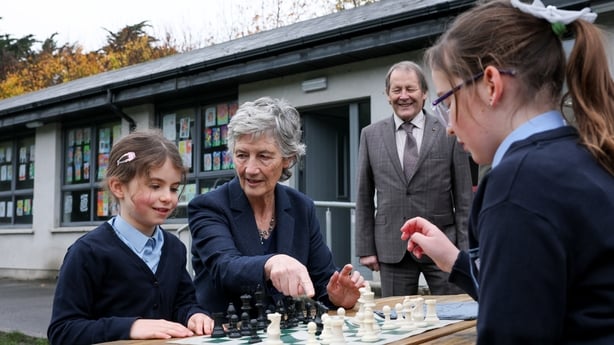 President Catherine Connolly and her husband Brian McEnery talk to members of the chess team at Gaelscoil Inse Chór in Inchicore
