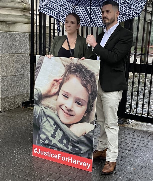 Gillian Sherratt and Stephen Morrison stand outside Government Buildings with a poster of their son Harvey
