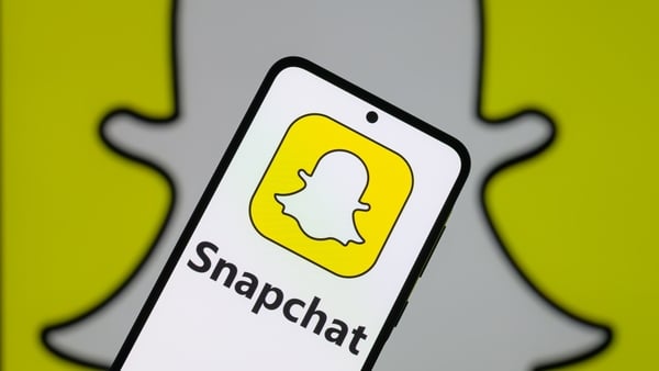 The Snapchat logo on a mobile phone with the Snapchat icon in the background