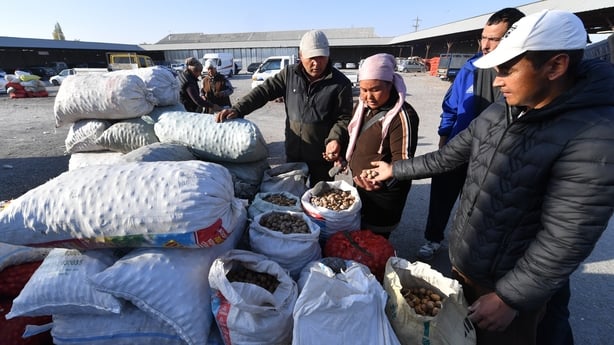 People buy and sell walnuts at a bazaar in a village 