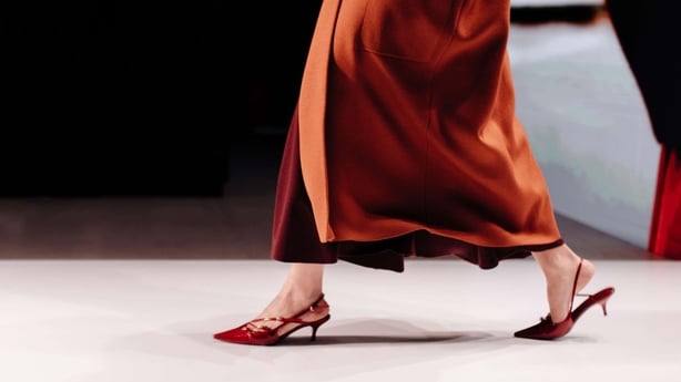 A woman wearing kitten heel sling back shoes and a dark orange skirt