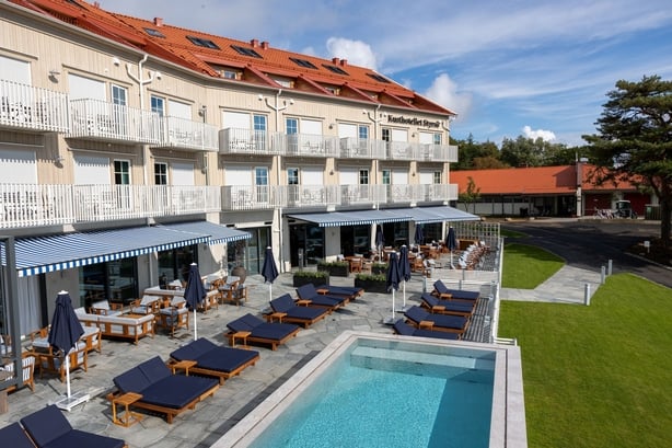 An external photo of a hotel with a pool and sun loungers