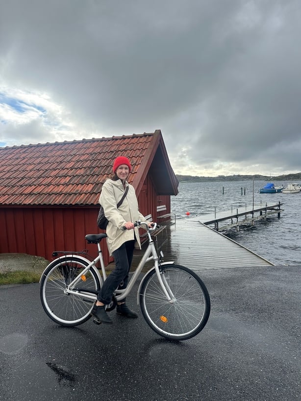 A photo of a woman on a bike beside a pier