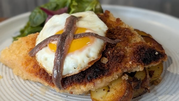A plate of pork schnitzel topped with fried egg