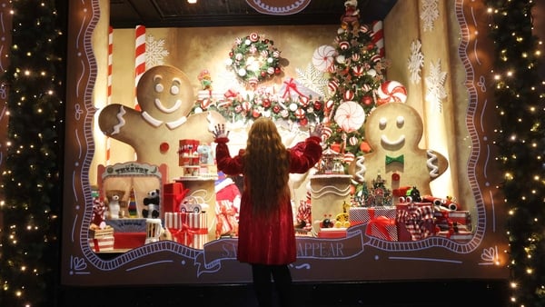 Girl in red coat looks at a Christmas window display