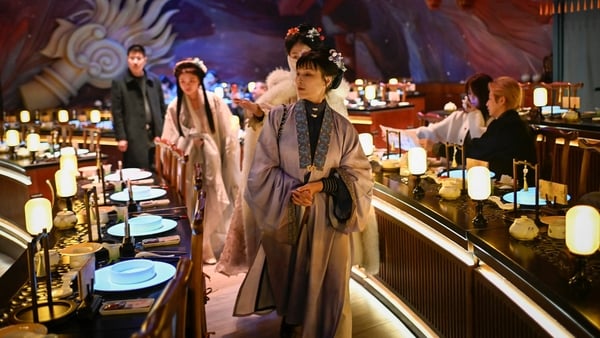 a woman wearing traditional Chinese clothes arriving for a meal at a theatrical restaurant