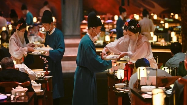 Waiters in traditional Chinese clothes serve food in a restaurant