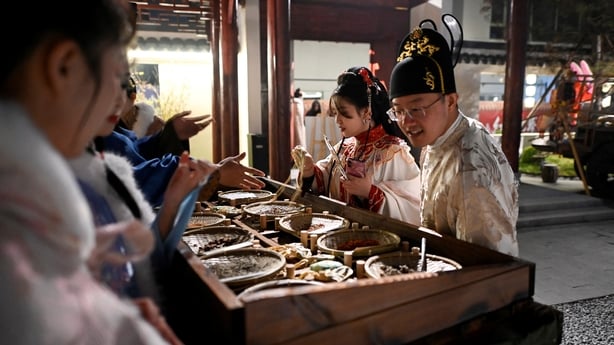 a couple in traditional Chinese clothes at an open market at a theatrical restaurant