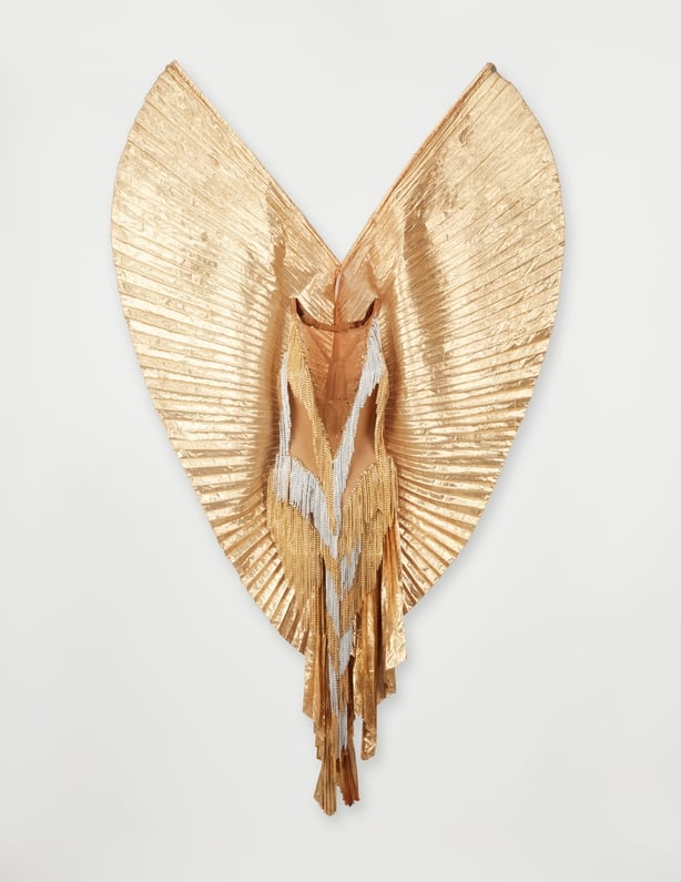 A gold winged bodysuit with gold and silver chains created by Bob Mackie