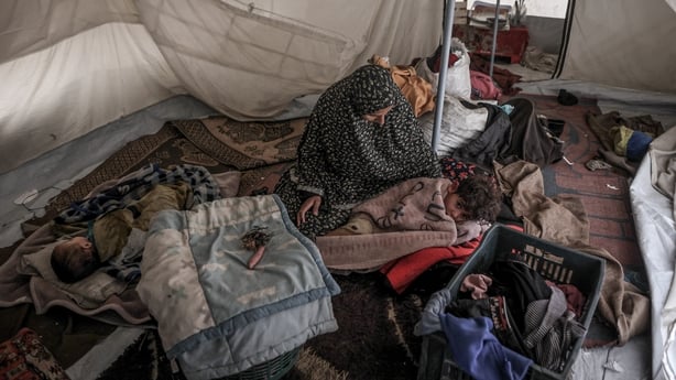 A Palestinian woman and her children sit in their shelter during the first winter rainfall on a displacement camp in Gaza City 